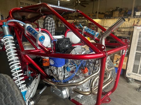 Red engine with blue components and coil springs mounted on red metal frame in workshop