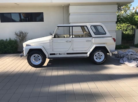 White Jeep-style four-door vehicle parked in a driveway in front of a modern garage